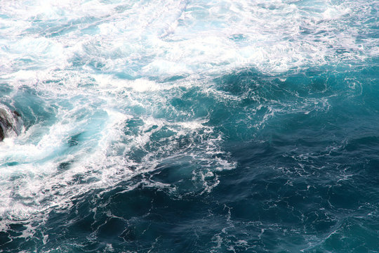 Blue gushing ocean. The waves of the ocean form a lot of white foam. Cropped shot, horizontal, a lot of free space for text, without people. Concept of nature and travel. © Nataliia