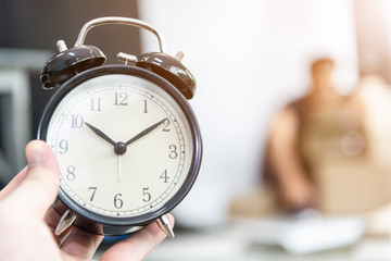 Alarm clock in hand with worker man is working always on time at work .Time working and deadline business  concept