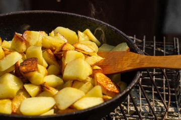 Potatoes fried in a frying pan on a grill