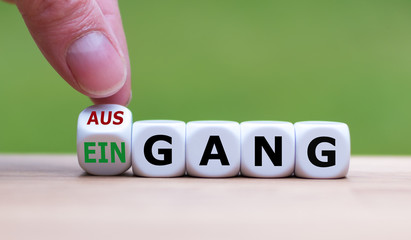 Hand dreht einen W&uuml;rfel und &auml;ndert das Wort "Ausgang" in "Eingang" (oder umgekehrt).