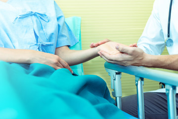 Closed up of Hands of doctor man reassuring woman patient on bed in  hospital .Professional medical doctor comforting patient at consulting room. Medical ethics and trust healthcare concept