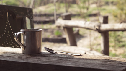 Metal mug and a spoon on a wooden table