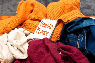 Clothes heap. there is a large pile of sketched clothes, notebook with please donate, coat drive,...