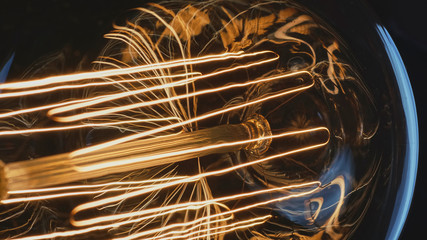 Macro shot of warm glowing carbon thread filaments of a vintage Edison light bulb.