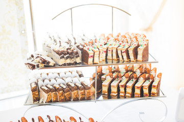 Delicious and tasty dessert table with cupcakes shots at reception closeup