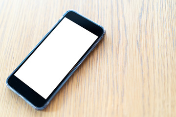 View of blank screen mobile phone on wooden table.