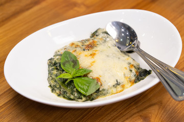 Close up of spinach with cheese on wooden table.
