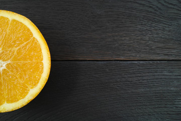 Orange on a dark wooden background. Top view. Half of an orange. Copy space