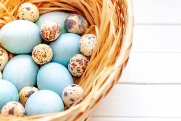 Easter eggs in the basket on a white wooden table.