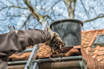Man on a ladder cleaning house gutters