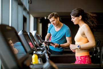 Close up of woman with trainer working out on treadmill in gym