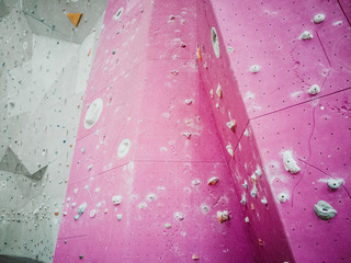 Pink wall with grey climbing holds for rock climbing activity.