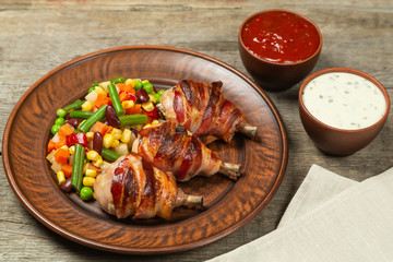 Fried chicken legs wrapped in bacon with vegetables