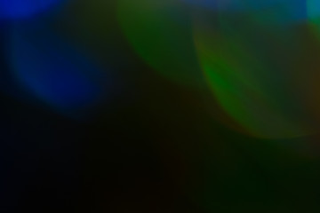 Blurred lens flare lights. Defocused dark abstract background. Glowing effect.