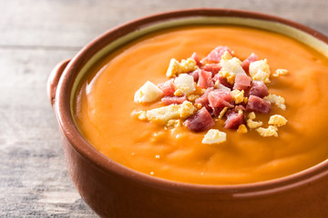 Typical Spanish salmorejo cream with ham and egg on wooden table. Close up