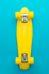 minimalist flat lay photo of cruiser skateboard over turquoise blue background © Ruslan Grumble