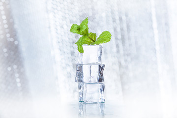 ice cubes and splashing water with mint on a colored background