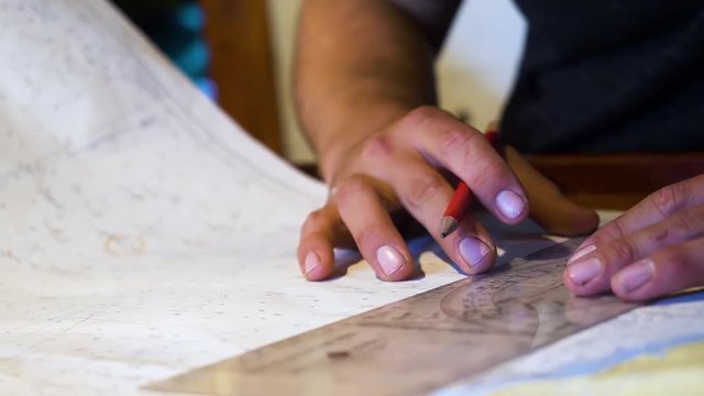 Close up of a sailing ships navigator preparing to plot a course at sea using a protractor