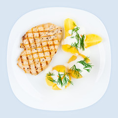 Fried chicken breast and boiled potatoes with dill and sour cream. Plate with tasty and healthy food, top view