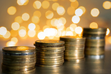 Money golden coins are putting with light beautiful bokeh at the background.