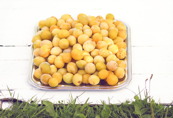 Fresh yellow plums. Ripe fruits in a wooden box on white boards background.
