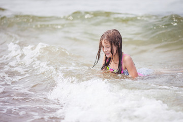 Cute girl swiming in the sea. Little girl froze, she is dissatisfied, it is a lot of splashes