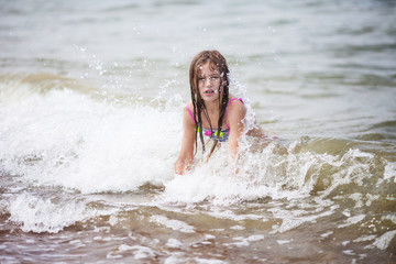 Cute girl swiming in the sea. Little girl froze, she is dissatisfied, it is a lot of splashes