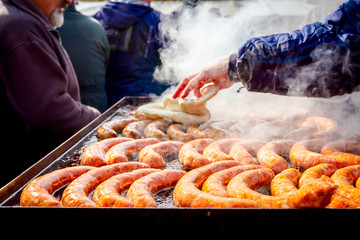 Baking delicious juicy sausages on the big barbecue plate