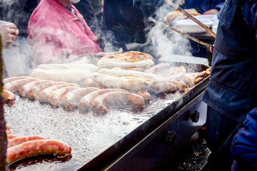 Turning delicious juicy sausages on barbecue plate with handle
