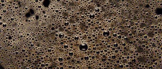 Panoramic shot of black coffee texture with bubbles
