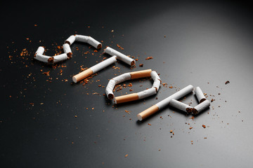 The inscription STOP from cigarettes on a black background. Stop smoking. The concept of smoking...