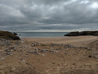 Fototapeta na wymiar Stormy, Cloudy Grey Welsh Coastline with Sandy Beach & Rocksand Waves