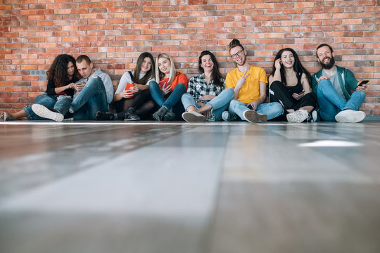 Millennials Happy Free Spirited Generation. Young Cheerful People Sitting On Floor, Hanging Out Together, Having Fun.