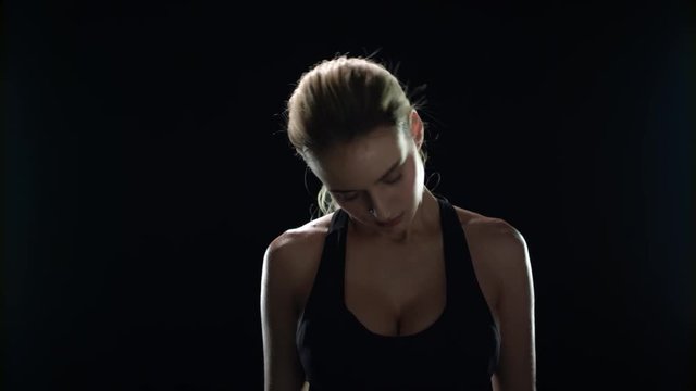 Sport woman doing warm up exercise for neck on black background