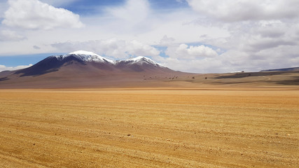 Desert landscape of the Andean plateau of Bolivia with the peaks of the snow-capped volcanoes of the Andes
