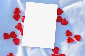 mock up white greeting card or invitation card on a white fabric background with hearts
