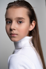 Portrait of a cute teen girl wearing a white turtleneck sweater. Isolated on gray background. Advertising, trendy and commercial design. Copy space