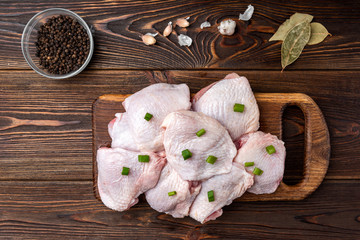 Raw chicken thighs on dark wooden background.