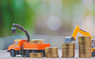 The yellow truck toy behind coins stack save the money invest for the future concept business, financial, tax and bonus. Logistics and transportation concept.