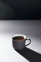 Cup of coffee on grey surface on black