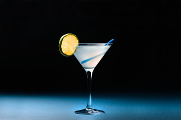 Classic Daiquiri cocktail with lime in martini glass on a dark blue background. Space for text.