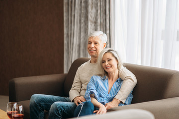 Mature husband and wife sitting on couch and hugs