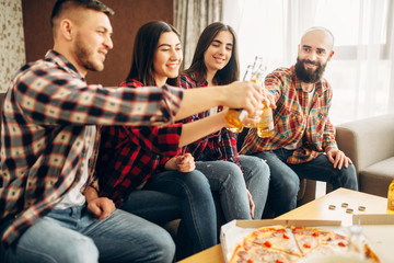 Friends clink bottles with beer at the home party