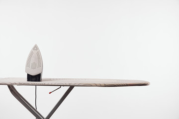 Ironing board with dark legs and iron isolated on grey