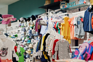 Children's bright clothes hang on the display in the baby clothing store.