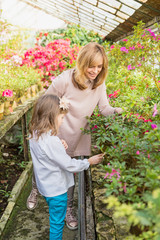 Mother And Daughter Growing Plants, gardening In Greenhouse.