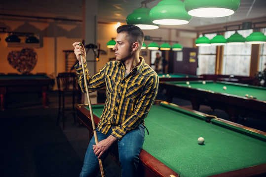 Male Billiard Player With Cue Poses At The Table