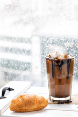 Rainy day coffee and croissant background with copy space.
