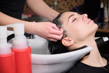 Hairdresser  washes  hair with shampoo to brunette  girl  in a beauty salon