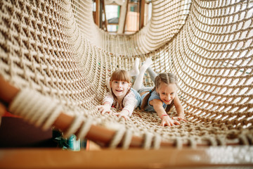 Two girls poses in rope net, children game center